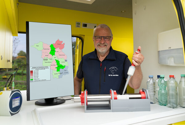Harald G�lzow untersucht eine Brunnenwasserprobe, mit Nitratkarte von Brandenburg im Labormobil vom VSR-Gew�sserschutz
